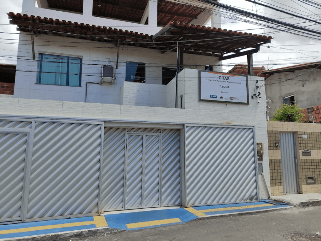 Fachada do CRAS Itapuã na Rua da Cacimba, em Salvador, com portões metálicos e placa identificando a unidade.