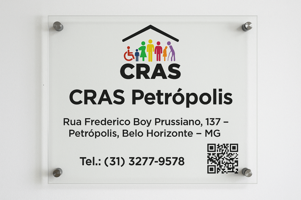Placa de vidro montada na parede com o logotipo colorido do CRAS e os dizeres CRAS Petrópolis, Rua Frederico Boy Prussiano, 137 – Petrópolis, Belo Horizonte – MG, telefone (31) 3277-9578 e QR Code para acesso à página da unidade.